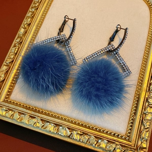 Macro detail of blue fur pom pom earrings with rhinestone geometric metal finish