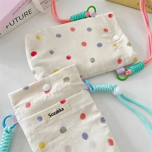 Detail of colorful polka dot canvas phone pouch with adjustable braided shoulder strap