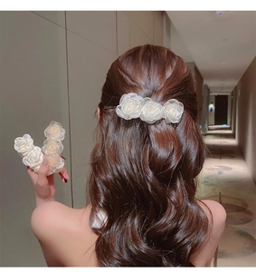 Detailed view of elegant white camellia flower hair clip on soft chiffon fabric