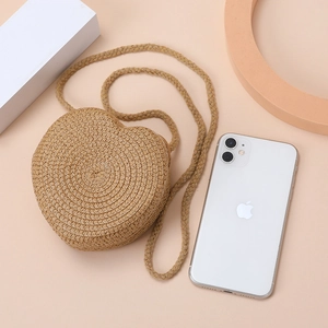 Detail of heart-shaped woven straw bag with textured strap and natural beige fiber patterns