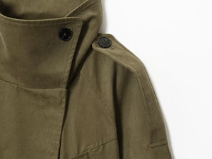 Detail eines militärgrünen Trenchcoats mit Stehkragen und Schulterklappen mit Nähten
