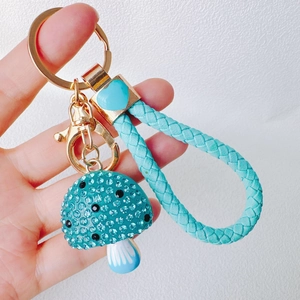 Detail of blue rhinestone mushroom keychain with gold hardware and woven strap