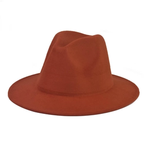Detail view of the rust red wool fedora hat featuring a classic flat brim and ribbon band