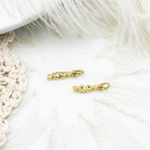 Macro shot of gold candy pendants with micro-pave crystals on soft white feathers