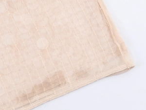 Dettaglio macro del tessuto a rete beige della gonna con paillettes e cuciture fini