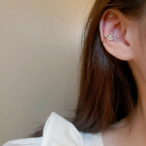 Detail of a golden butterfly ear cuff with sparkling rhinestones worn on the ear