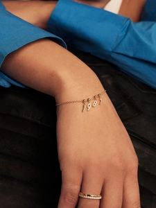 Close-up of a gold S925 sterling silver chain bracelet featuring a 1987 number charm