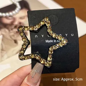 Close-up of a 5cm star-shaped hair clip with yellow rhinestones on a metal base