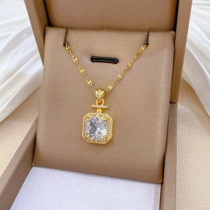Détail du pendentif flacon de parfum doré avec cristaux sur satin blanc soyeux