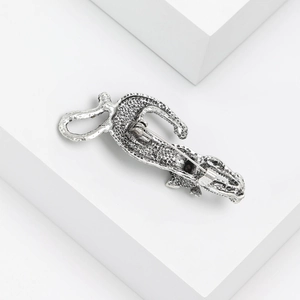 Silver lizard brooch with natural abalone shell and crystal inlay on a white pedestal