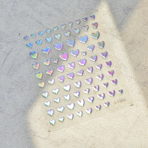 Detalle macro de pegatinas 5D holográficas para uñas con refracción láser metálica y relieve