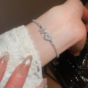 Detail of silver-toned zircon heart and star charm bracelet on female wrist
