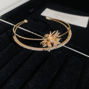 Macro detail of a double-layered gold bracelet with zircon starburst and pavé stones