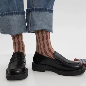 Gros plan sur des chaussettes en coton à rayures marron avec mocassins en cuir noir