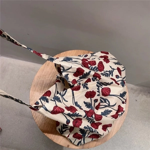Detail view of red floral poppy print on a soft beige cotton tote bag fabric texture