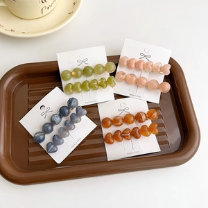 Candy-colored heart resin hair clips in olive, peach, and blue on gold alligator base