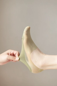 Close-up of light green low cut liner sock showing elastic heel and breathable fabric