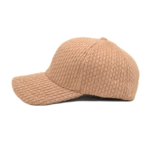 Macro shot of camel knit baseball cap showing thick yarn texture and curved brim detail