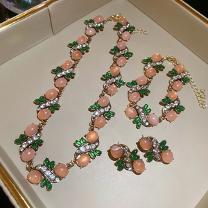 Elegant vintage jewelry set with pink oval resin stones and crystals on a golden tray