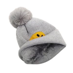 Detail der grauen Strickmütze mit dickem Plüschfutter und großem Kunstfell-Bommel