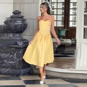 Detail of yellow corset midi dress with satin finish and elegant flared skirt