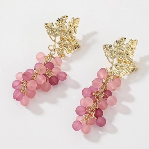 Macro detail of gold grape leaf earring with pink and purple matte bead cluster charms