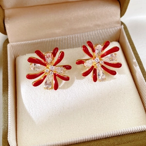 Detail of red enamel flower earrings with zircon center in a green velvet jewelry box