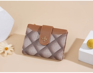 Close-up of brown plaid fold wallet with gold cross emblem and textured leather flap