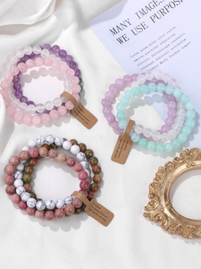 Detailed view of layered natural crystal bead bracelets in purple, pink, and green tones