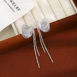 Silver butterfly tassel earrings with sparkling rhinestones on brown leather surface