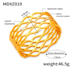 Detailed view of wide titanium steel hollow wave bangle with gold finish and Czech diamonds