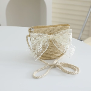 Close-up of girls beige straw crossbody bag with white lace bow and zipper detail