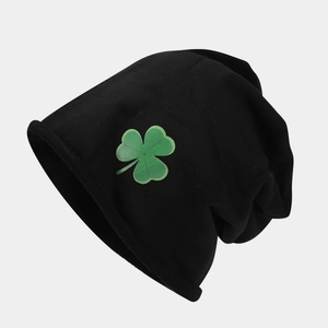 Dettaglio del berretto nero in maglia con motivo a trifoglio verde e trama soffice