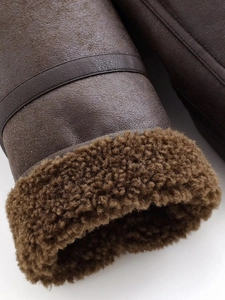 Detailed close-up of dark brown suede leather jacket cuff with thick faux shearling lining