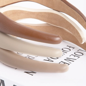 Close-up of textured faux leather headbands in earthy tones with premium stitching detail