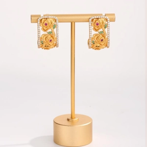 Detail of gold floral hoop earrings with pink and green gemstones on a jewelry display