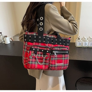 Detail of red plaid tote bag with metal eyelets, rivets and decorative chains