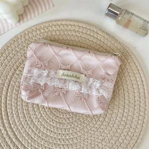 Detailed macro view of pink quilted lace coin purse with delicate ribbon embroidery