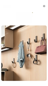 Detail of matte black metal J-hook mounted on wood wall for hanging daily accessories