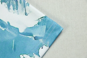 Detail of double-needle stitching and blue abstract print on soft knit fabric