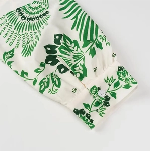 Detail of white shirt cuff with green tropical leaf prints and single button closure