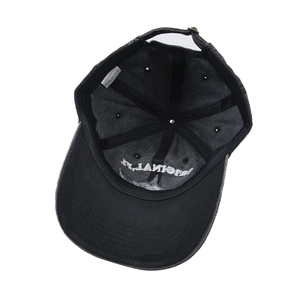Detail of black cotton baseball cap showing 100% cotton wash label and metal buckle