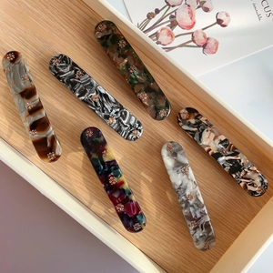Macro shot of six marble texture acetate hair clips with small flower decorations