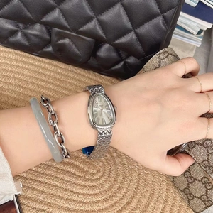 Close-up of elegant silver snake-head watch with triangle dial on female wrist