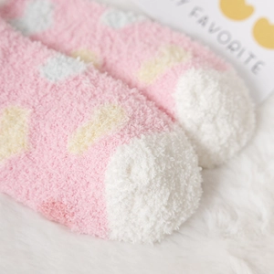 Close-up of pink coral fleece socks with soft heart patterns and fluffy warm texture