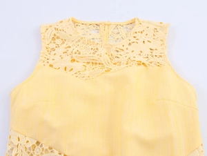 Close-up of yellow sleeveless top featuring delicate lace patchwork and hollow out patterns