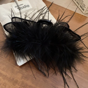 Detail of black feather hair claw clip with mesh bow on dark wooden background