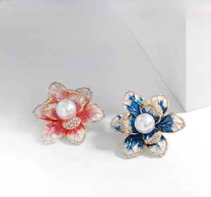Macro shot of enamel flower brooches with pink and blue petals and pearl centers