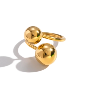 Detailed view of golden stainless steel open ring with two polished geometric metal balls