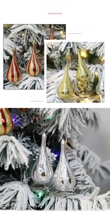 Glittery teardrop Christmas ornaments in red gold and silver on a snowy pine tree
